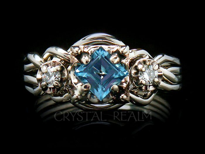Guinevere four band puzzle ring with step cut blue topaz and two five point round diamonds