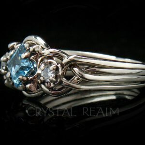 Guinevere puzzle ring in four bands with blue topaz center stone and side diamonds